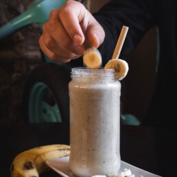 person putting sliced banana fruit on top of jar