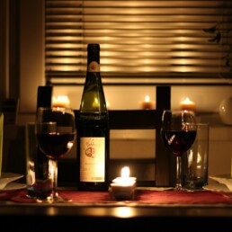 wine glass filled with wine beside bottle on table